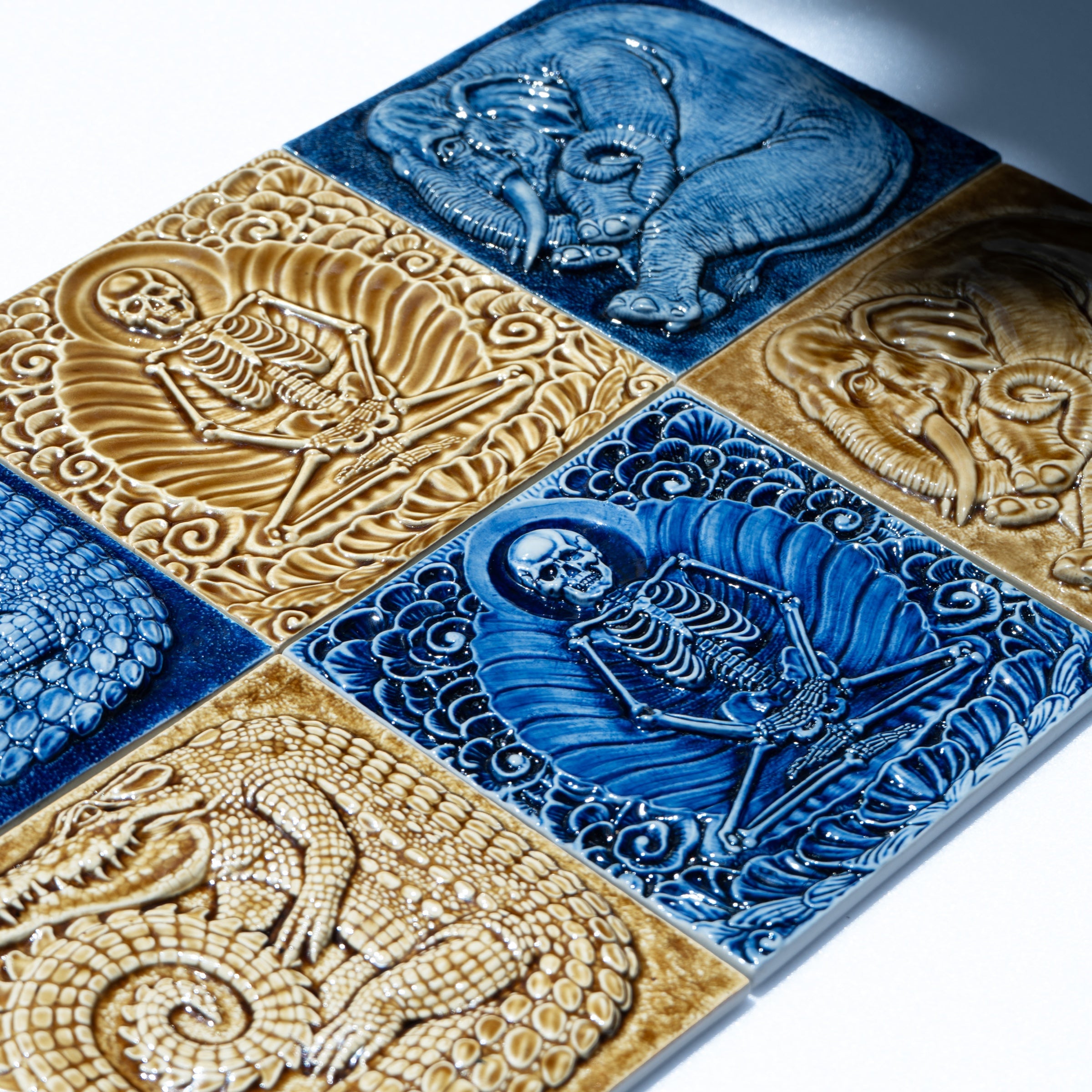 Six bas-relief tiles in cobalt and amber glazes, seen at an angle